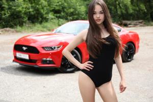 Симпатичная милая девушка позирует на фоне красного Ford Mustang