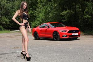 Симпатичная милая девушка позирует на фоне красного Ford Mustang