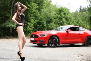 Симпатичная милая девушка позирует на фоне красного Ford Mustang