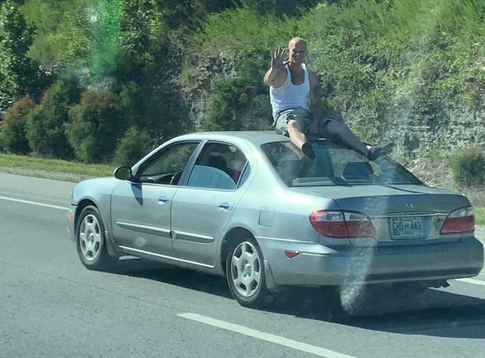 человек едет на крыше автомобиля